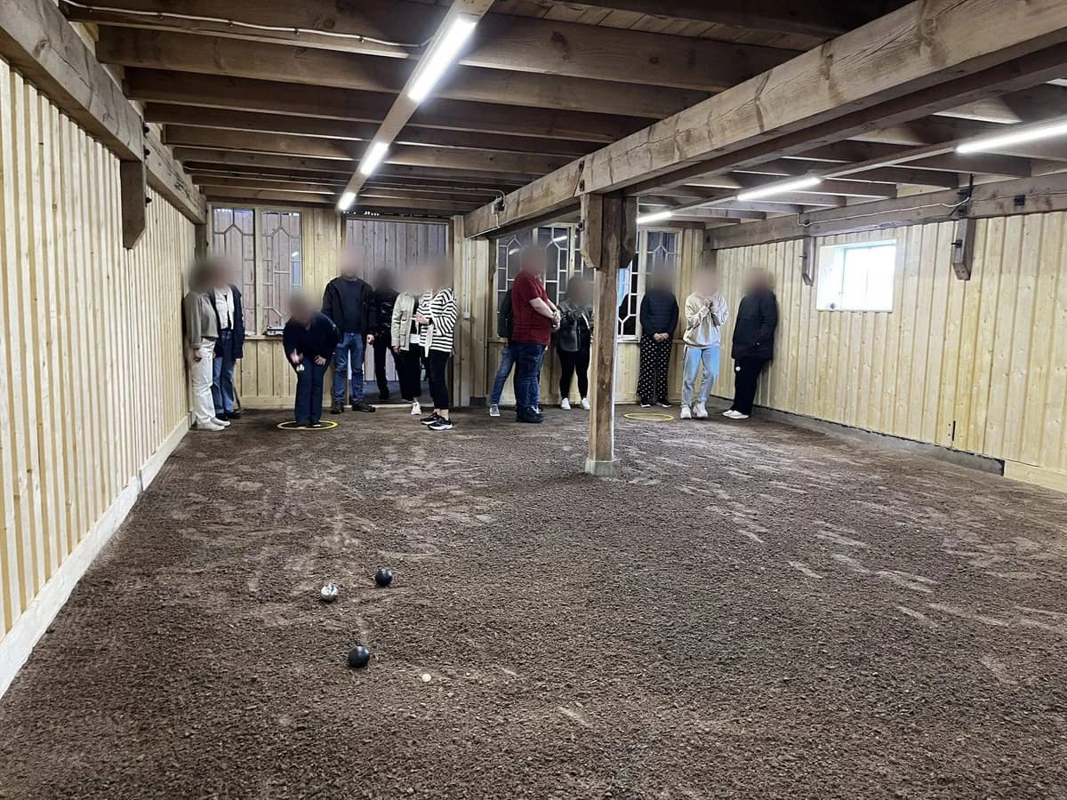 Ett gäng spelar boule på inomhusbanan i ladugården.